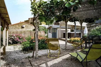 a patio with chairs and a table under a tree at Côté Vignes à Bélesta in Bélesta
