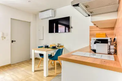 a kitchen with a table and a small kitchen with blue chairs at EDEN SUITE - Jacuzzi - Parking - Clim by Narbana in Narbonne
