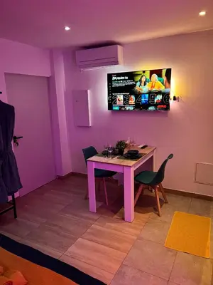 a purple room with a table and a tv on the wall at EDEN SUITE - Jacuzzi - Parking - Clim by Narbana in Narbonne