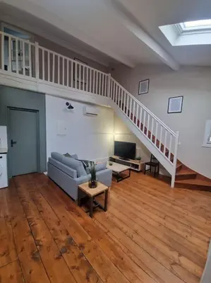 a living room with a couch and a stair case at La Marceline 1 - Appart entre mer et canal du midi en pays Cathare in Saint-Marcel