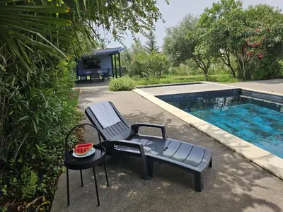 a chair and a table next to a swimming pool at Clos des Oliviers in Oupia