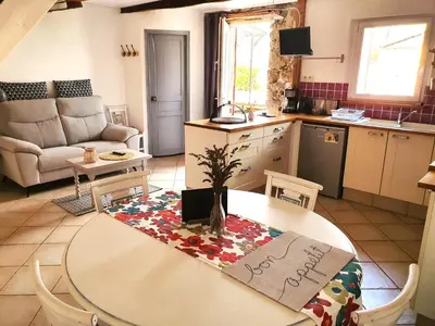 a kitchen and living room with a table with a sign on it at Les pieds en éventail in Lignairolles