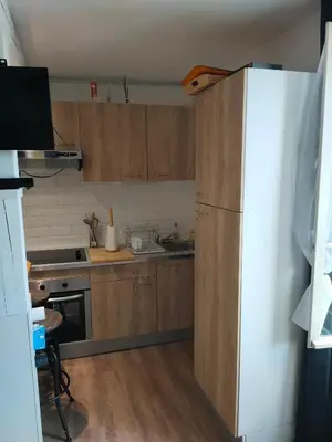 a kitchen with wooden cabinets and a white refrigerator at Le quai in Port-la-Nouvelle