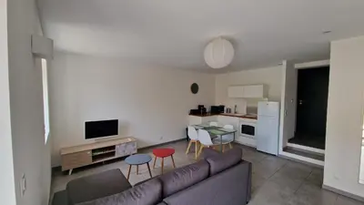 a living room with a couch and a kitchen at Résidence du Portail d'Avail in Sigean