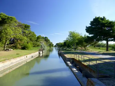 a river with a bridge and a boat on it at Résidence du Portail d'Avail in Sigean