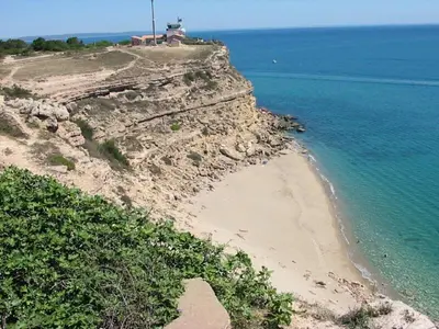 a beach with a lighthouse on top of a cliff at Résidence du Portail d'Avail in Sigean