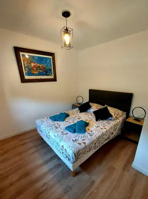 a bedroom with a bed with blue pillows on it at La Belle Vie en Alaric in Douzens