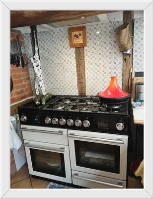 a stove top oven in a kitchen with a red lamp at Symphony du Vivant in Lautrec