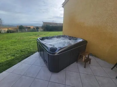 a hot tub sitting on the side of a building at Adorable guest house with piscine and spa in Lempaut