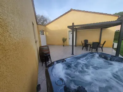 a hot tub on a patio with a table and chairs at Adorable guest house with piscine and spa in Lempaut