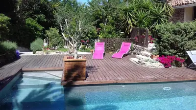 two pink chairs sitting on a deck next to a swimming pool at Gîte du caveau in Marcorignan