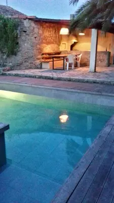 a swimming pool in front of a house with a table at Gîte du caveau in Marcorignan