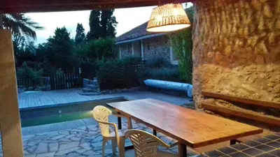 a wooden table and chairs on a patio at Gîte du caveau in Marcorignan