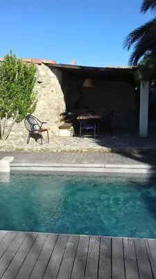 a pool with two chairs and a table next to a house at Gîte du caveau in Marcorignan
