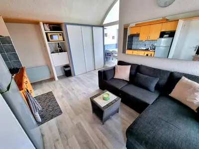 a living room with a black couch and a table at Bellyenmer Gruissan in Gruissan
