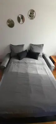 a bed with gray sheets and pillows in a bedroom at Sur les pas de Pierre Paul Riquet in Montferrand