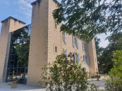 a large brick building with windows and a tree at Domaine de ferrabouc in Mas-Saintes-Puelles
