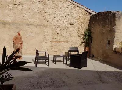 a patio with chairs and a statue in a wall at Les treilles d'en Peyre in Nogaret