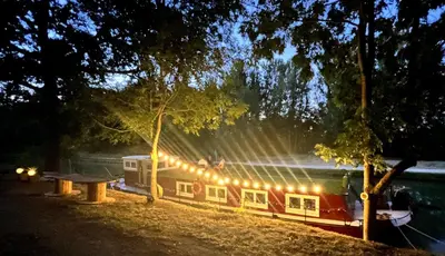 a boat parked next to a picnic table next to a lake at Péniche Dondon - Gîte cocooning sur Canal du midi in Avignonet-de-Lauragais