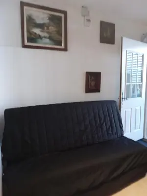 a black couch sitting in a room next to a door at Joli Studio avec jardin in Espira-de-lʼAgly