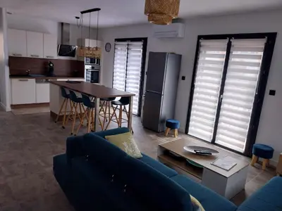 a living room with a blue couch and a kitchen at Appartement fonctionnel proche du centre ville in Narbonne