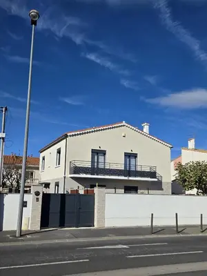 a white house with a balcony on a street at Appartement fonctionnel proche du centre ville in Narbonne
