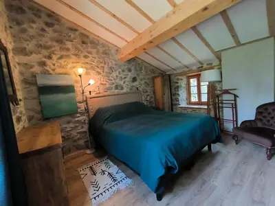 a bedroom with a bed in a room with stone walls at Gite du grand cèdre in CampÃ´me