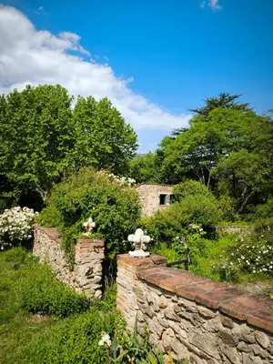 a garden with a stone wall and flowers at Gite du grand cèdre in CampÃ´me