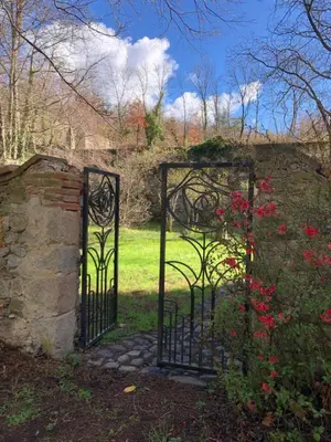 an entrance to a garden with a gate with flowers at Gite du grand cèdre in CampÃ´me