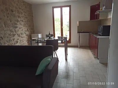 a kitchen with a table and some chairs in a room at Porte Rouge in Capendu