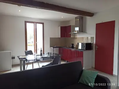 a living room with a table and a kitchen at Porte Rouge in Capendu