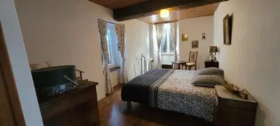 a bedroom with a bed and a bathroom with a tub at Grande maison de montagne rénovée, du charme in Rodome