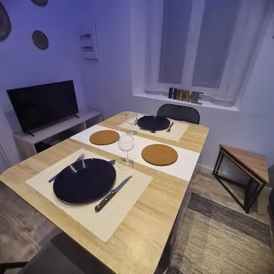 a table with a plate and wine glasses on it at Très joli appartement 2 pièces, centre-ville in Tuchan