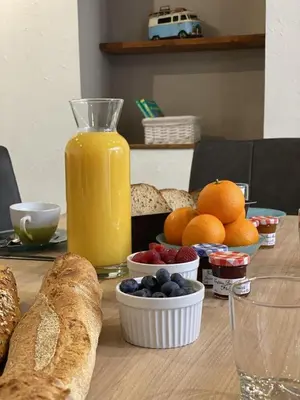 a table with bread and oranges and a jug of orange juice at Le Gîte du Canal, à Homps. in Homps