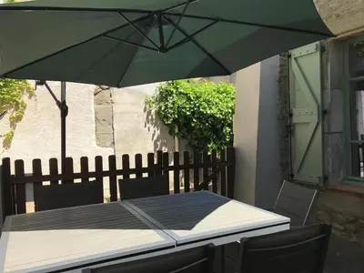 a table with a green umbrella on a patio at Le Gîte du Canal, à Homps. in Homps
