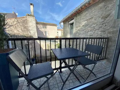 a balcony with two chairs and a table on a balcony at Le Gîte du Canal, à Homps. in Homps