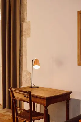 a wooden table with a lamp and a chair at Gîte Superbe L'Ecurie XIXème in Sallèles-dʼAude