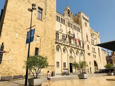 a person walking in front of a large building at Appartement Terrasse proche centre et canal in Narbonne