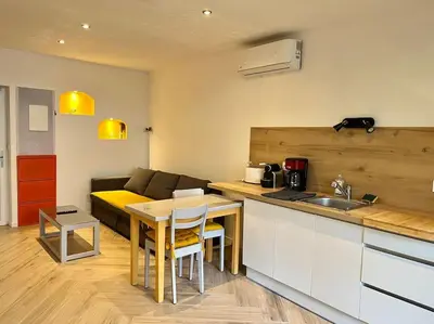 a kitchen and living room with a table and a couch at Appartement Terrasse proche centre et canal in Narbonne