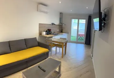 a living room with a couch and a kitchen at Appartement Terrasse proche centre et canal in Narbonne
