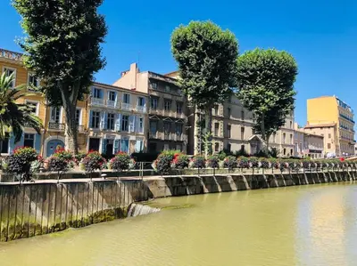 a river in a city with buildings and trees at Appartement Terrasse proche centre et canal in Narbonne