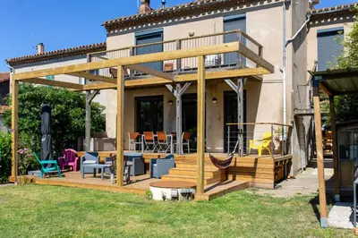 a wooden deck with a patio and a house at Maison, piscine & vue sur la Cité de Carcassonne in Carcassonne