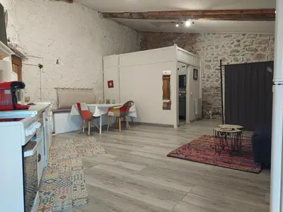 a living room with a table and a kitchen at Gite Studio Les Maisons de Gaïa in Tuchan