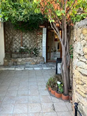 a stone building with a tree in front of a door at Gite Studio Les Maisons de Gaïa in Tuchan