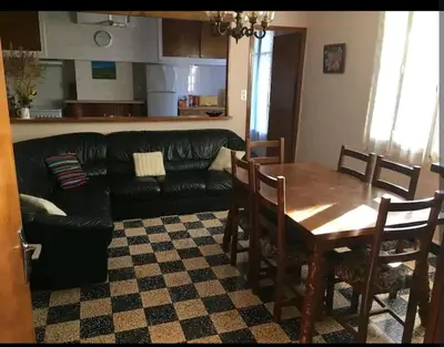 a living room with a table and a black leather couch at Grand Appartement 6 pers,lumineux,avec terrasse Sud de France in Tuchan