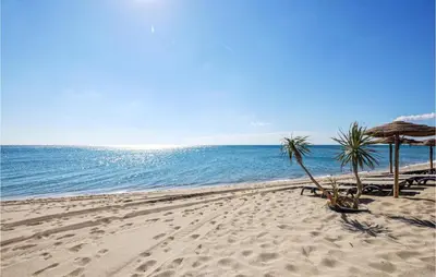 a beach with chairs and umbrellas and the ocean at Awesome Home In Villeneuve-Lès-Montréa in Villeneuve-lès-Montréal