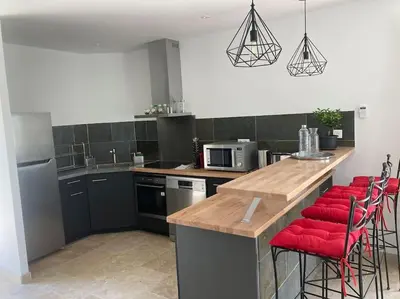 a kitchen with a counter with red stools in it at Gîte Ardoise in Castelnaudary