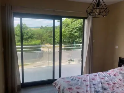 a bedroom with a large window with a view of a balcony at Gîte Ardoise in Castelnaudary