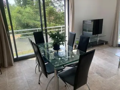 a dining room with a glass table with chairs and a television at Gîte Ardoise in Castelnaudary