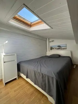 a bedroom with a large bed and a skylight at La maisonnette de Gruissan in Gruissan